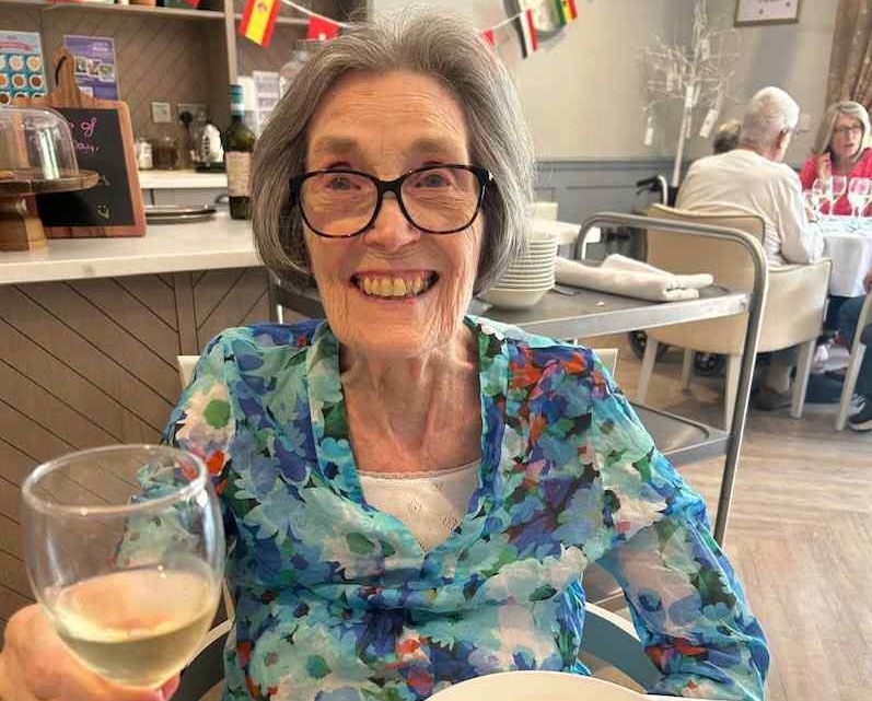 small version of nursing care resident enjoying a glass of wine