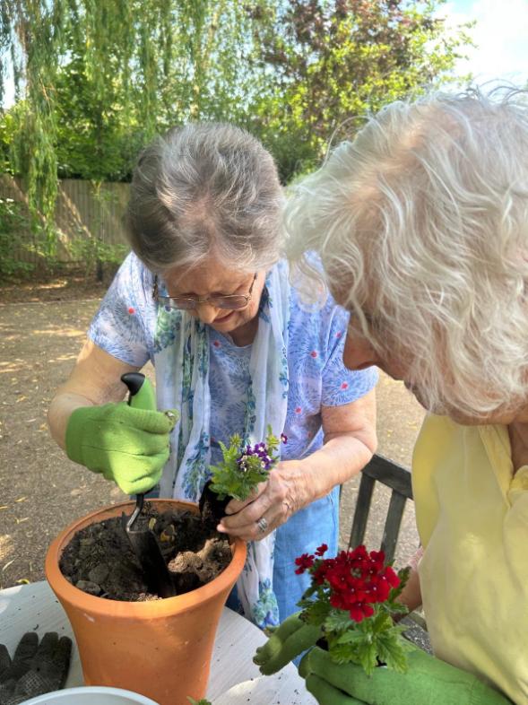 older ladies putting soil in a plant pot