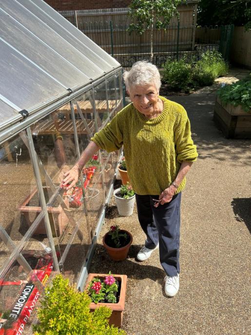 older lady stood by a greenhouse