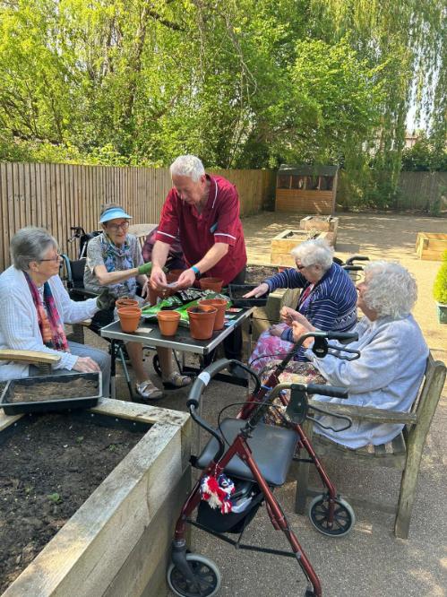 residents and a carer using plant pots together