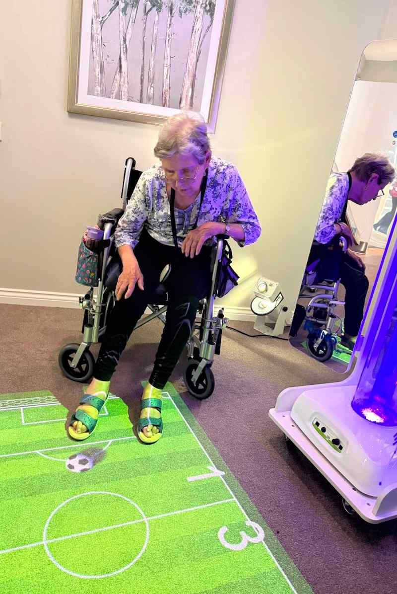 resident playing interactive football on a pitch that has been projected onto the floor in a lounge