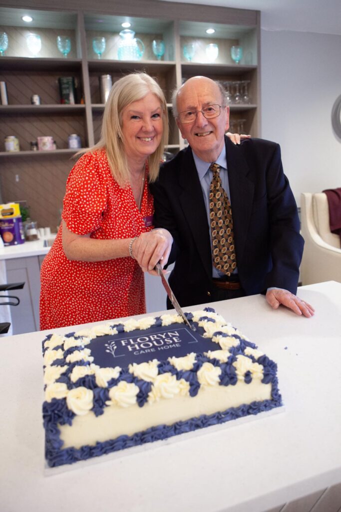 our home manager and one of our residents cutting a cake for our grand opening