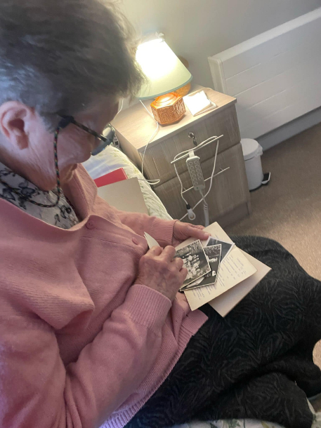 female resident sat on her bed looking at pictures of loved ones