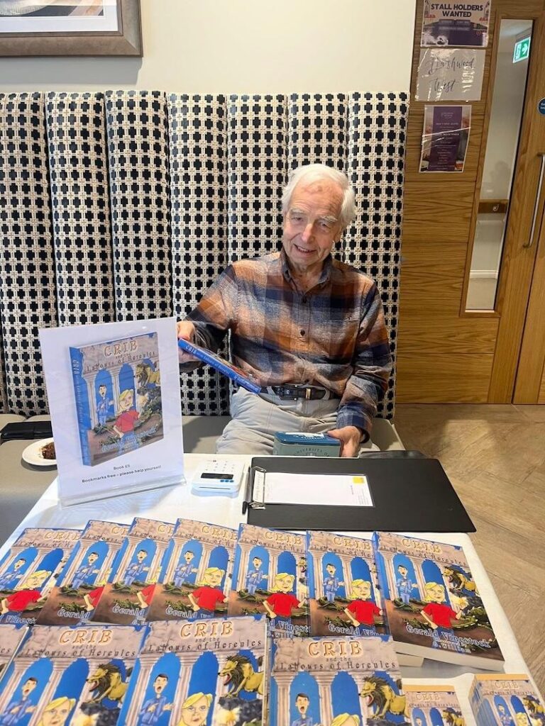 male resident sat on a bench selling books at our open day