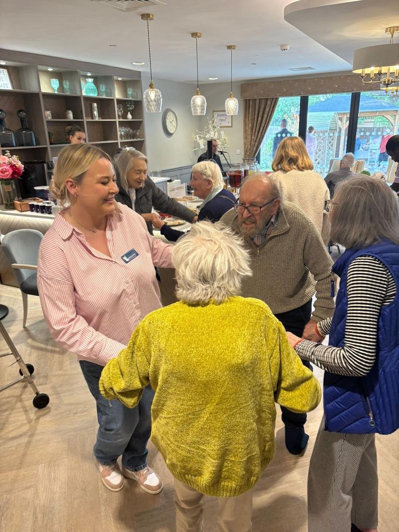 residents and carers all holding hands and dancing to an entertainer in the cafe