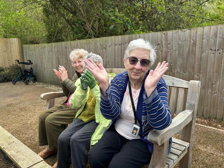 three older ladies sat on a bench clapping