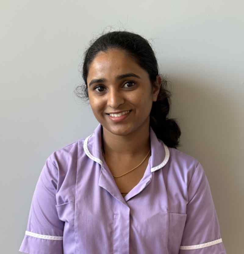 female care assistant stood smiling wearing a lilac nurse uniform