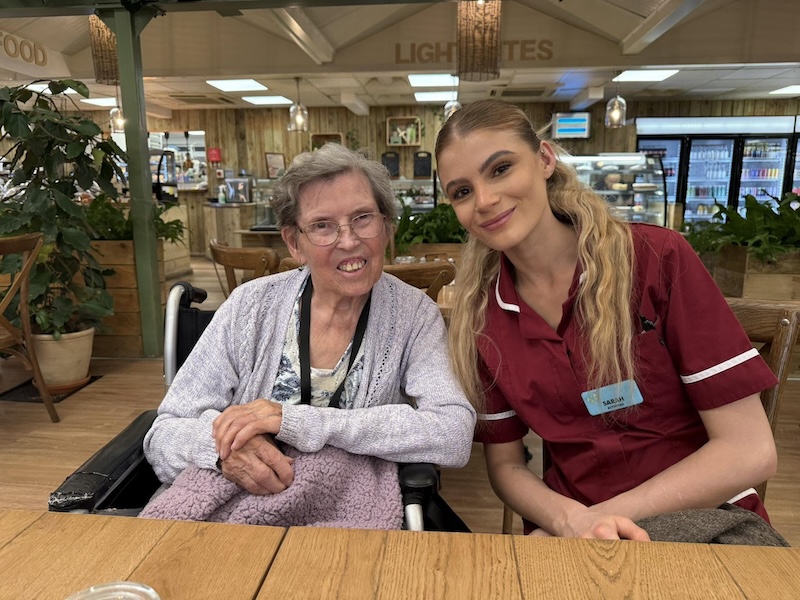 one of our residents sat at a local cafe with one of our activities coordinators