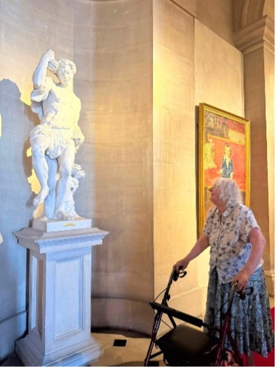 an older lady looking at a sculpture